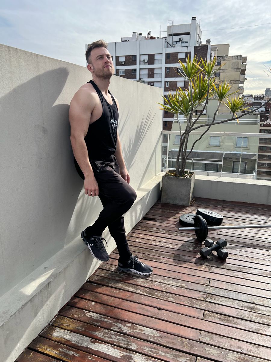 Jota, entrenador personal de Bestial, apoyado en una pared junto a una barra en una terraza de Buenos Aires